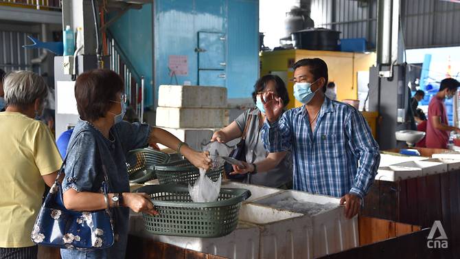 Chia Tian Seng (right) attends to a customer at the fishery he and his brothers founded. Before this, Mr Chia worked as a fisherman. (Photo: Vincent Tan)